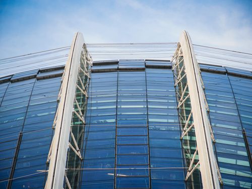 Free Close-up of a modern glass building with a blue sky background, showcasing sleek architecture. Stock Photo