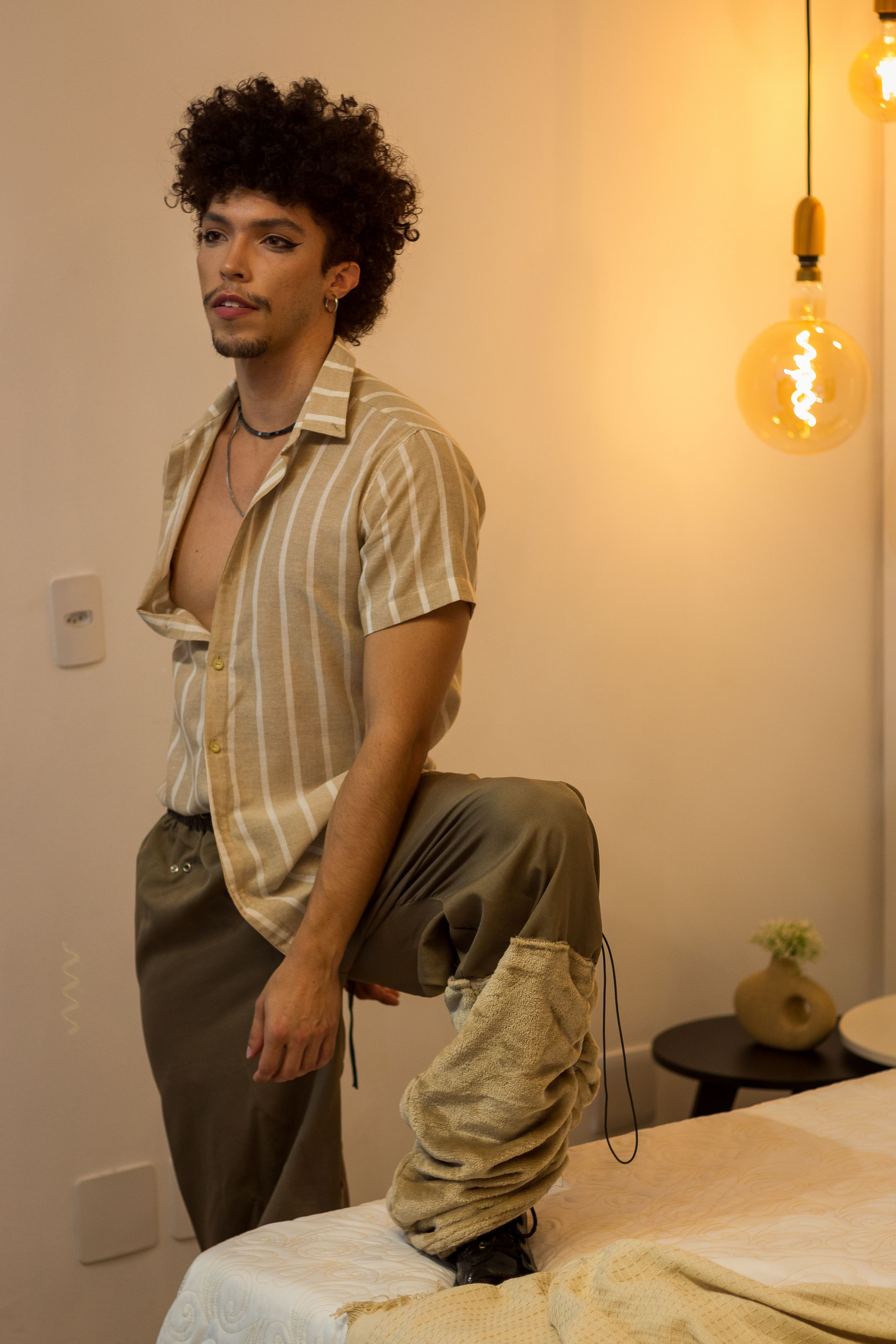 Fashionable young man in modern room with warm lighting, posing confidently.
