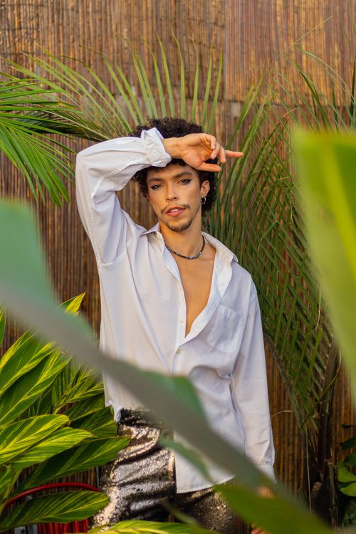 Free Stylish young man poses amidst lush tropical plants, exuding confidence and elegance. Stock Photo
