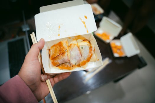 Delicious Taiwanese street food crepes drizzled with sauce in a takeout box, served with chopsticks.