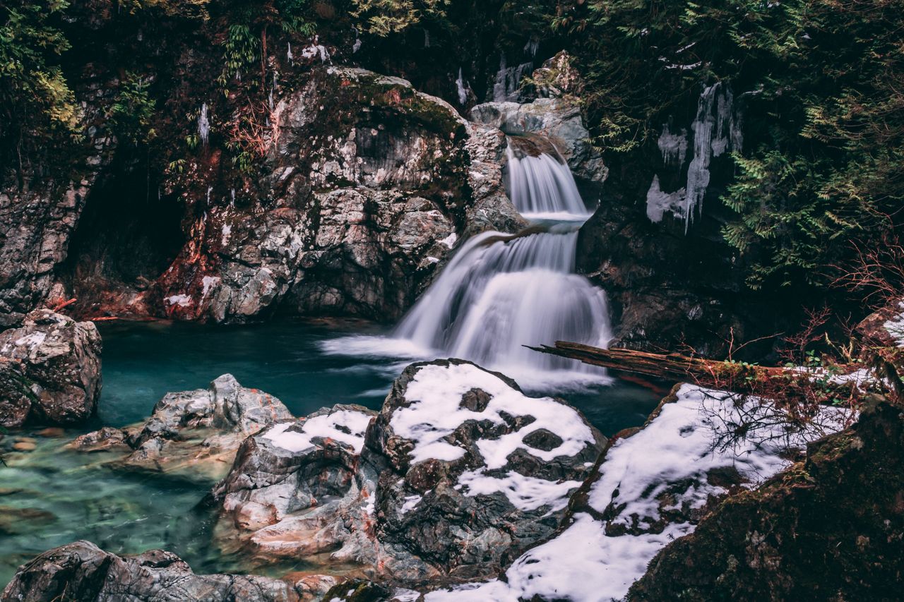 peaceful waterfall cascading through snowy rocks in a tranquil forest