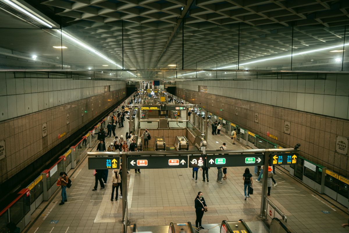 Busy Taipei Metro station with commuters on escalators and platforms