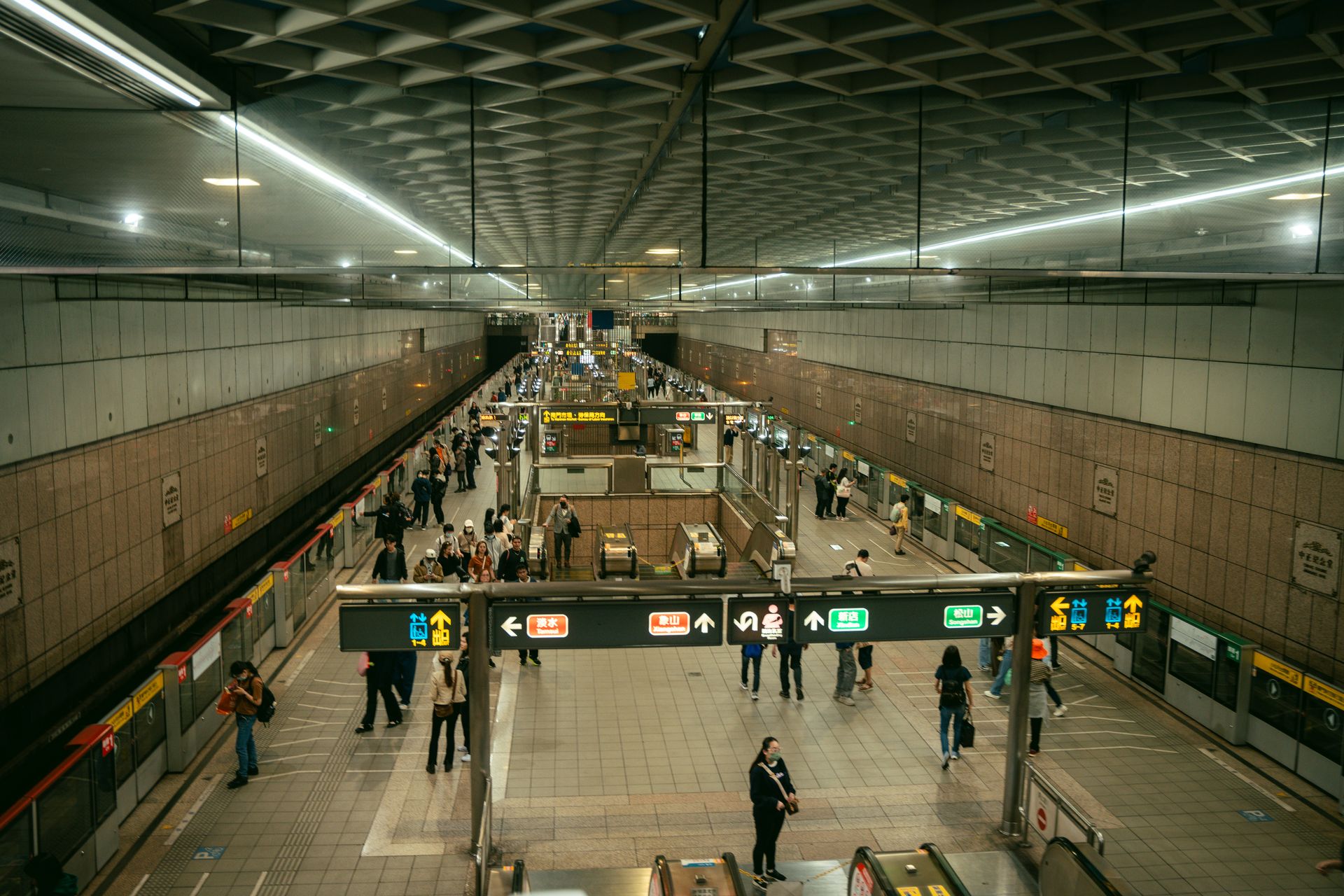 A busy Taipei Metro station with commuters navigating escalators and platforms during rush hour.