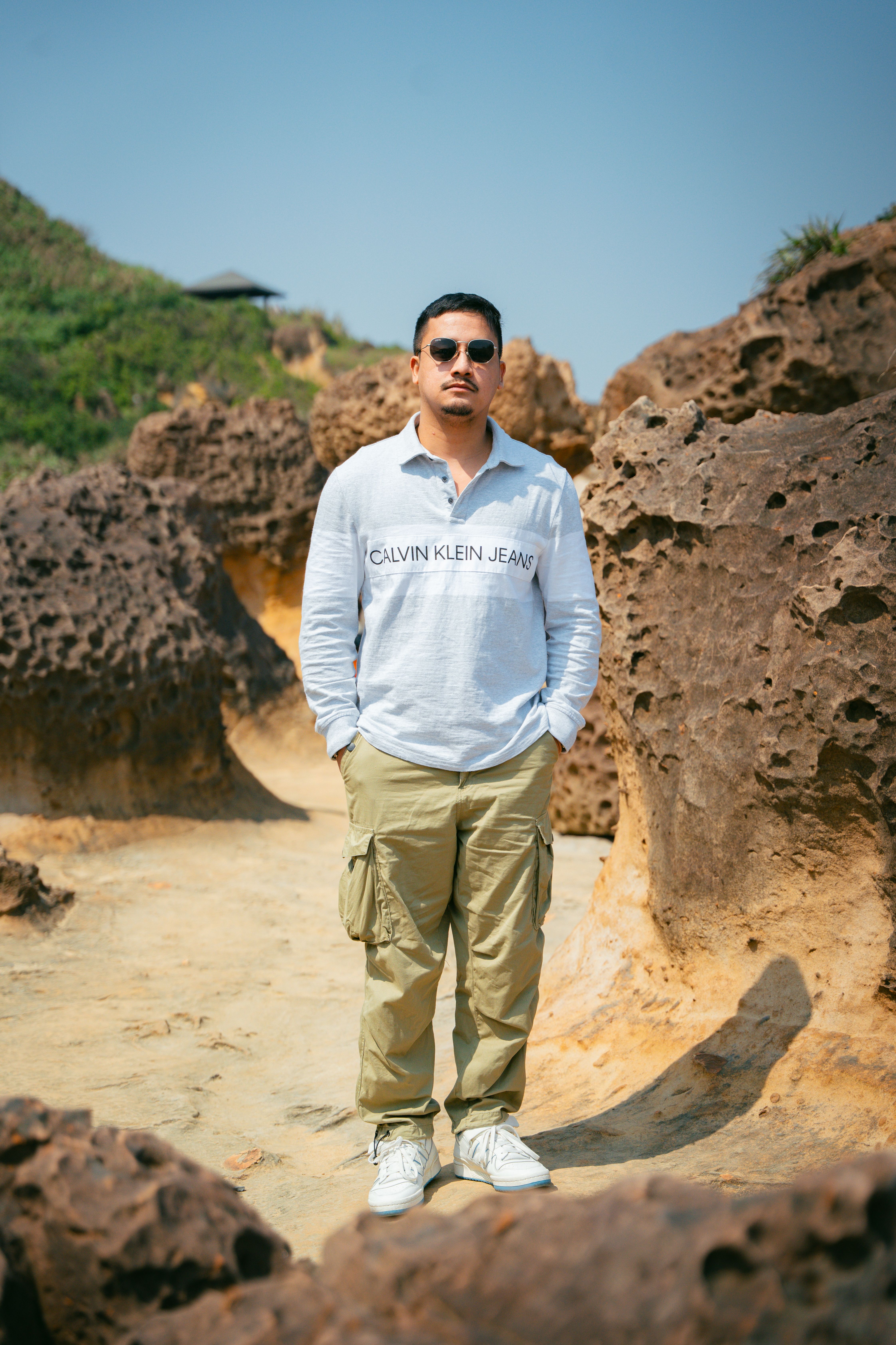 Man in sunglasses exploring rugged outdoor landscape under blue sky.