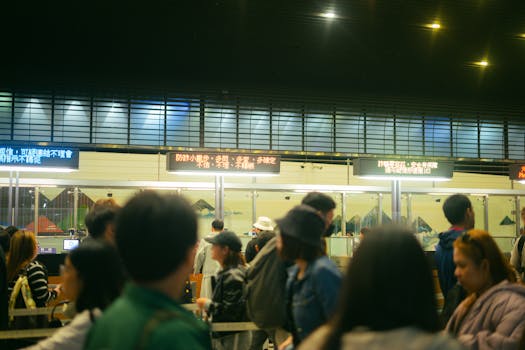Airport customs check - Crowded airport check-in area with people queueing and visible flight information signs.