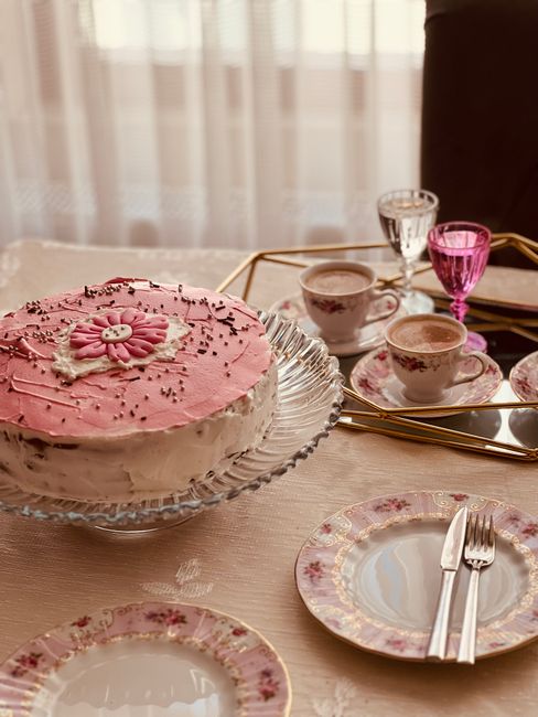 Beautifully decorated pink floral cake with elegant tea set arrangement, perfect for afternoon tea gatherings.