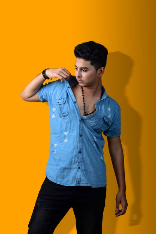 Free Stylish young man posing in a denim shirt against a vibrant background. Stock Photo