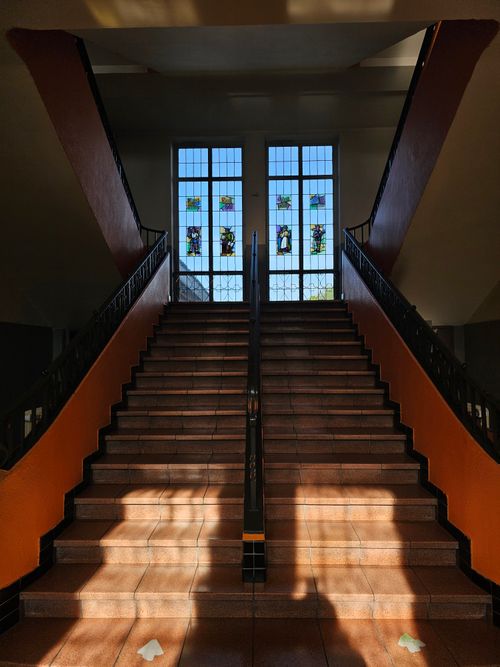 Free Interior view of a grand staircase with beautiful stained glass windows, offering a warm and inviting ambiance. Stock Photo
