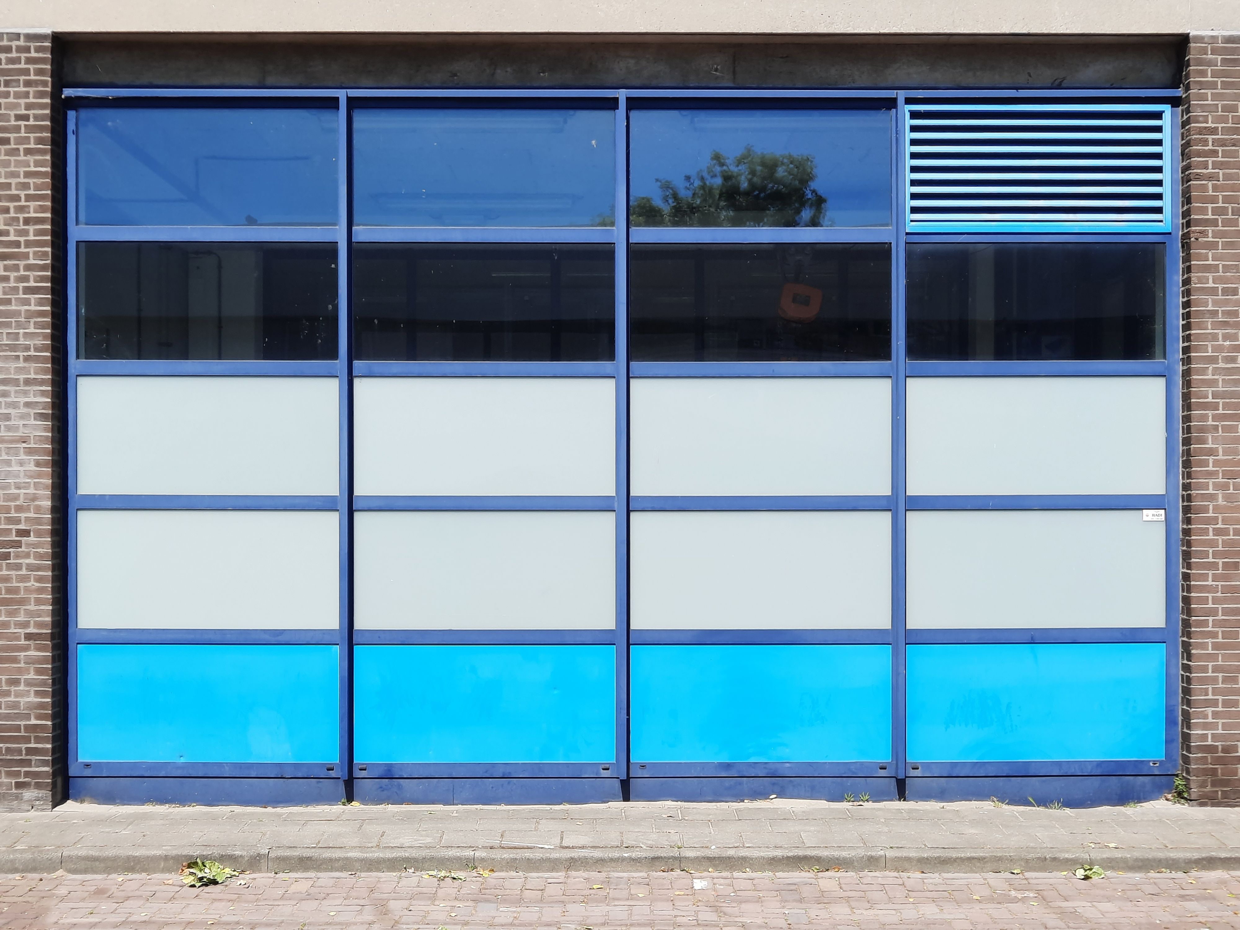 A modern garage door with blue and glass panels, showcasing contemporary architecture.