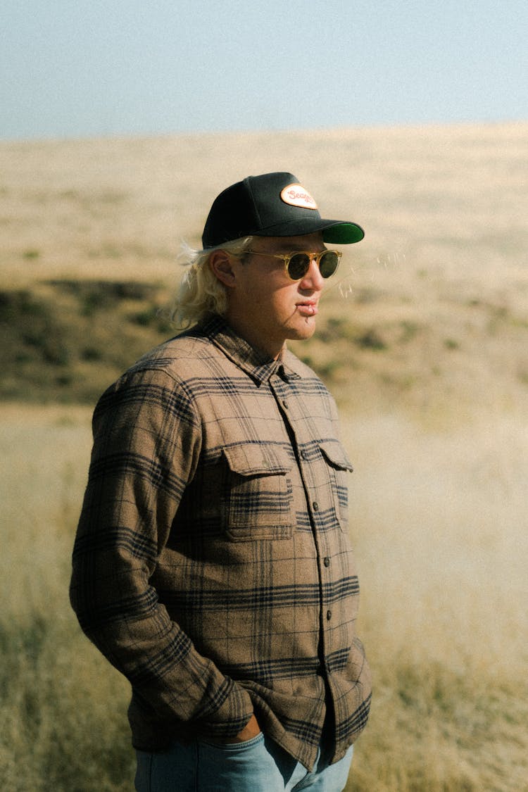 Man In Baseball Hat Standing In Barren Field