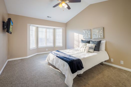 A spacious bedroom with neutral tones and modern decor, captured in natural light.