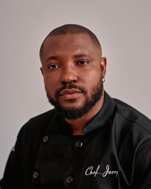 Free Portrait of a professional chef wearing a black uniform with a neutral background. Stock Photo