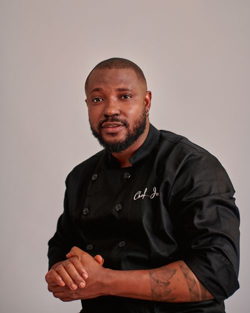 Free Portrait of a confident black male chef in a classic black uniform against a neutral background. Stock Photo