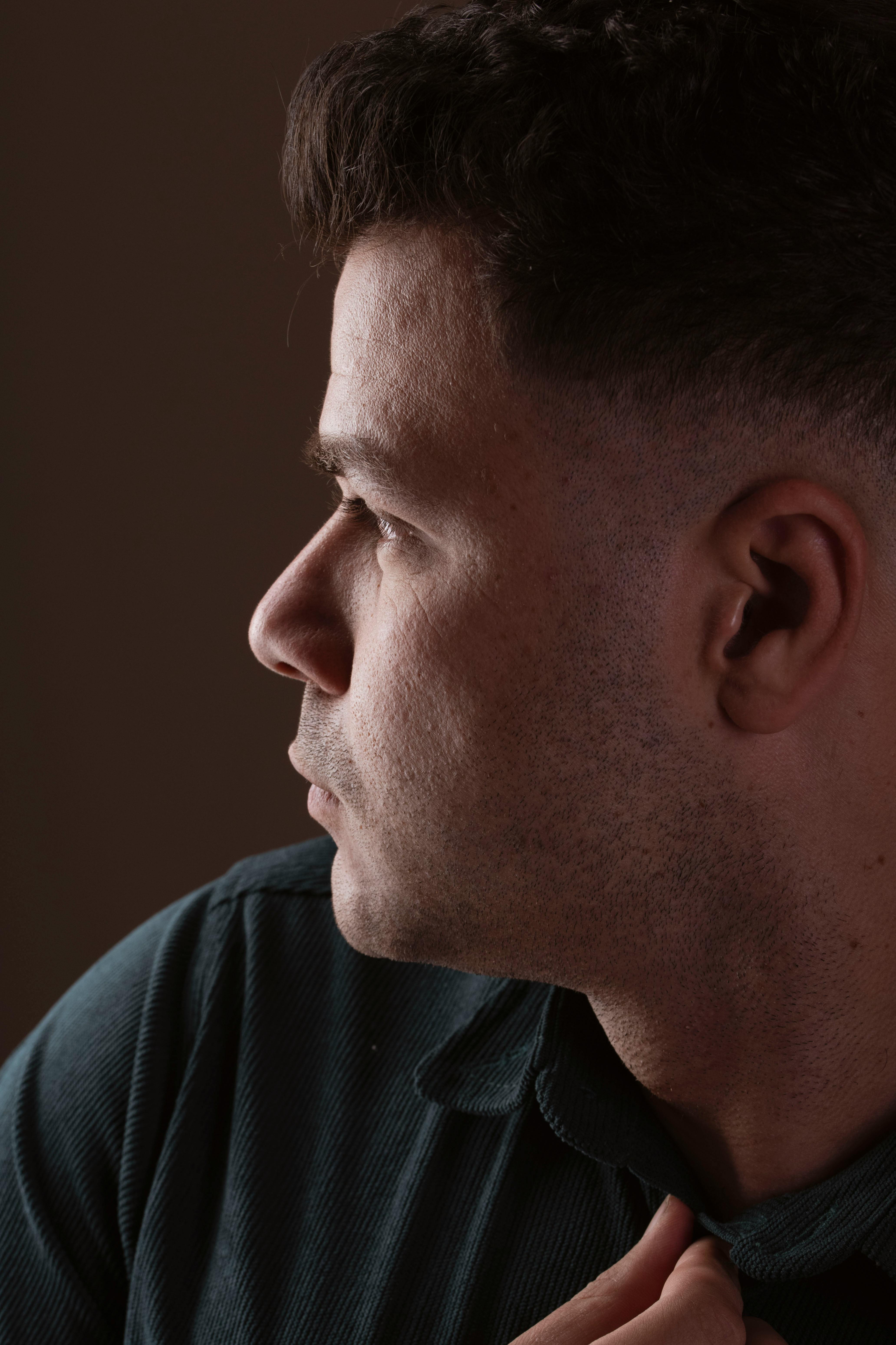 Side profile portrait capturing a man in contemplation, highlighting emotions through soft lighting.