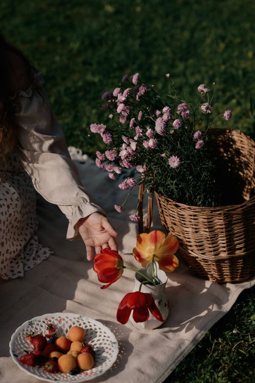 Free A serene summer picnic scene featuring flowers and a plate of fresh fruit. Stock Photo