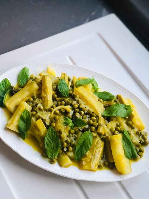Free Delicious vegetarian dish featuring peas and potatoes garnished with fresh mint leaves on a white plate. Stock Photo