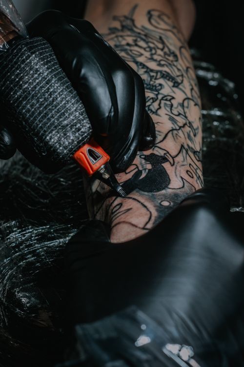 Free Intricate black tattoo being inked by a gloved artist, showcasing detailed artistry on arm. Stock Photo