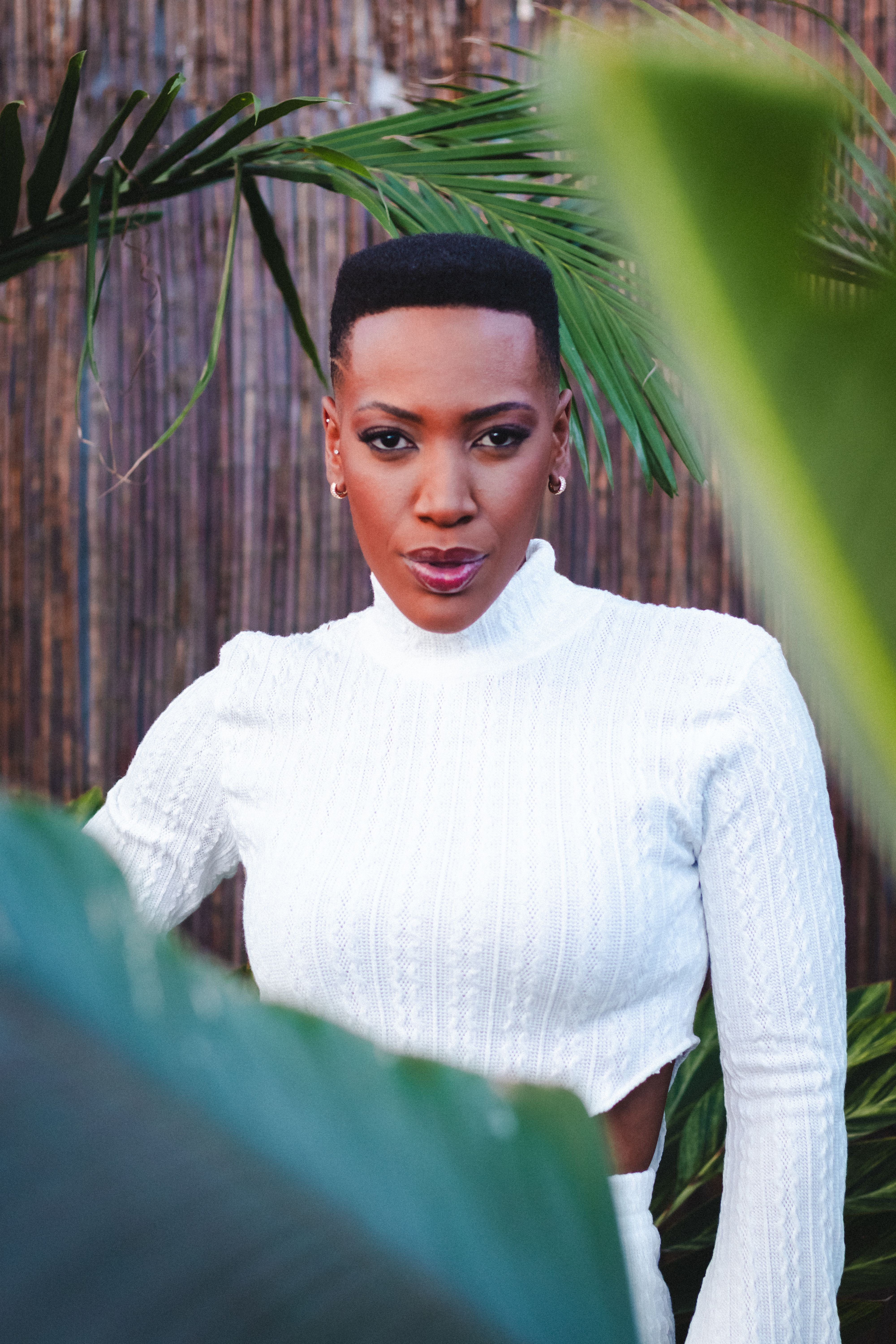 Stylish portrait of a woman framed by lush greenery, showcasing elegance in São Paulo.