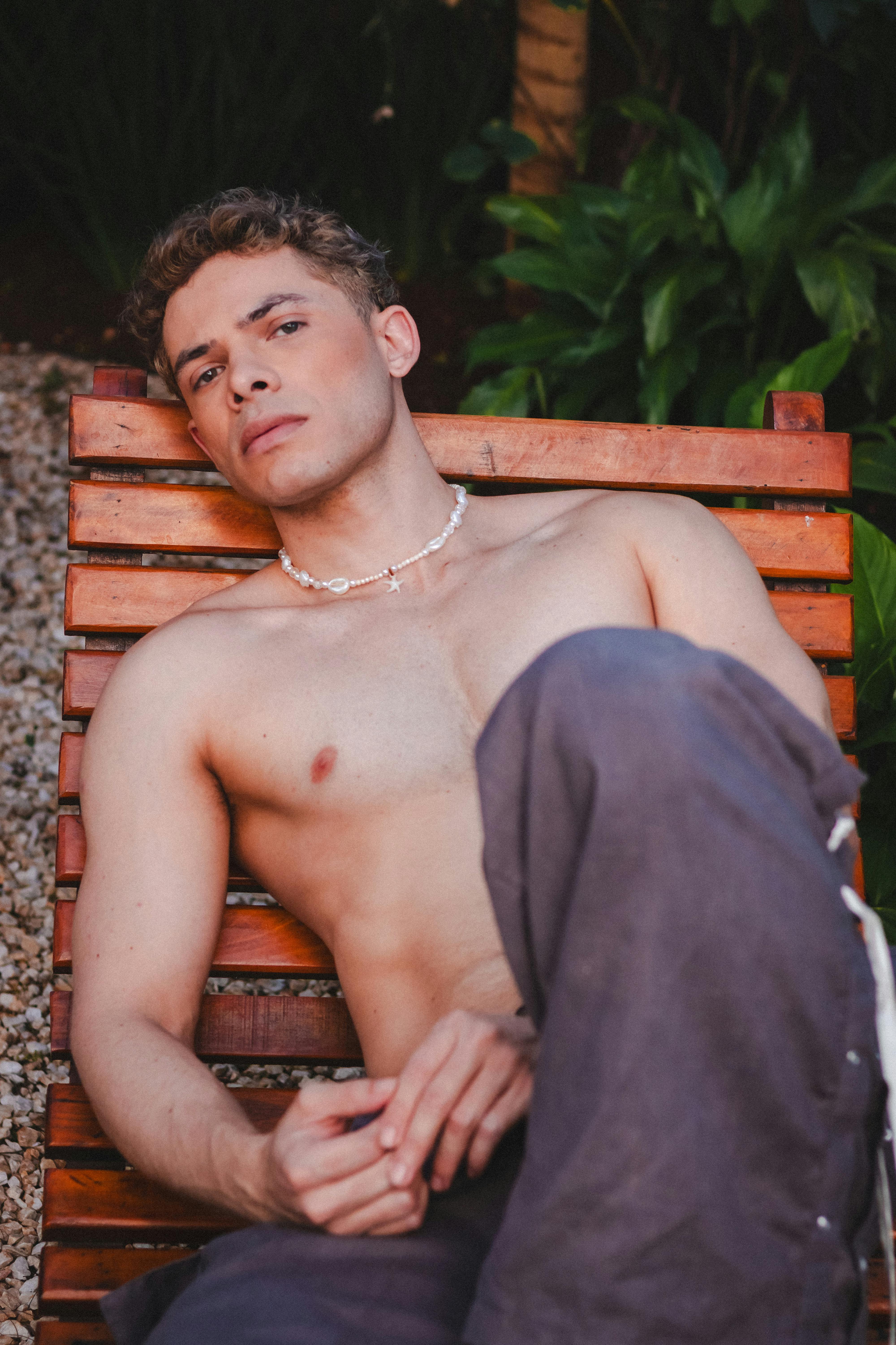 A serene outdoor portrait of a man lounging on a wooden chair amidst lush greenery in São Paulo.