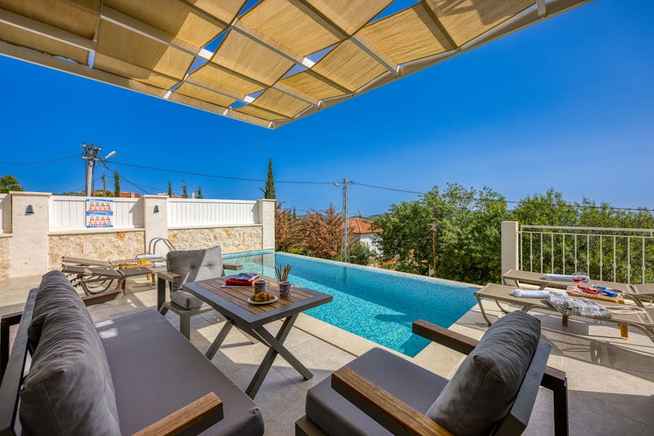 Relaxing poolside setting with comfortable seating and ocean view under a shaded pergola.