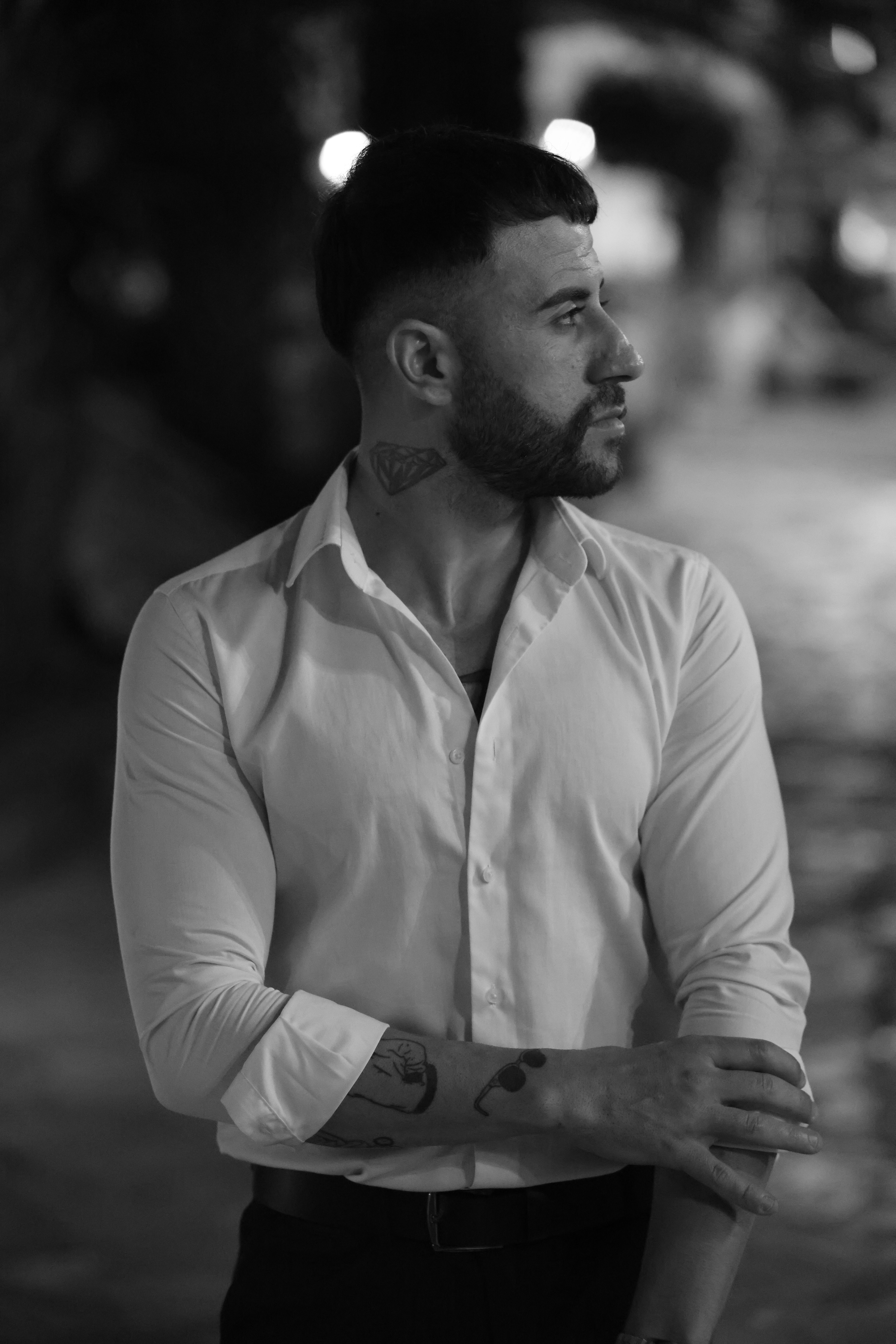 無料 夜に横を向いているスタイリッシュな白いシャツを着た男性の白黒ポートレート。 写真素材