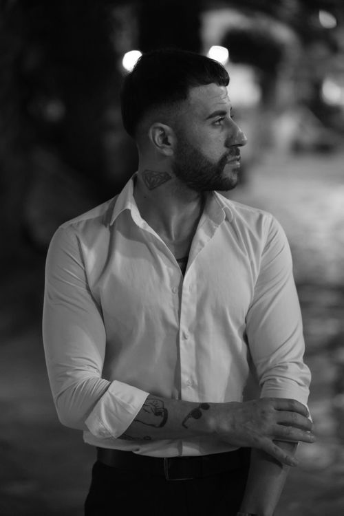 Free Black and white portrait of a man in stylish white shirt looking to the side at night. Stock Photo