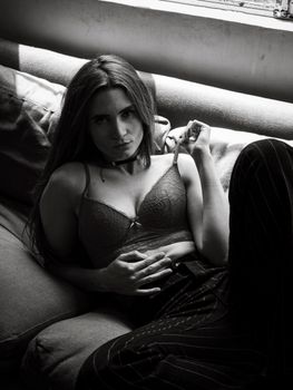 Artistic black and white portrait of a woman in lingerie lounging on a sofa.