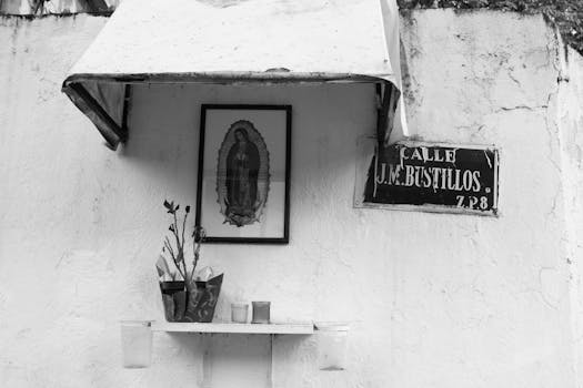 Black and white photo of a street shrine with a religious icon and Calle J.M. Bustillos sign.