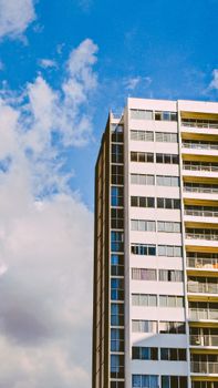 A modern high-rise building with a blue sky and scattered clouds backdrop, showcasing urban architecture.
