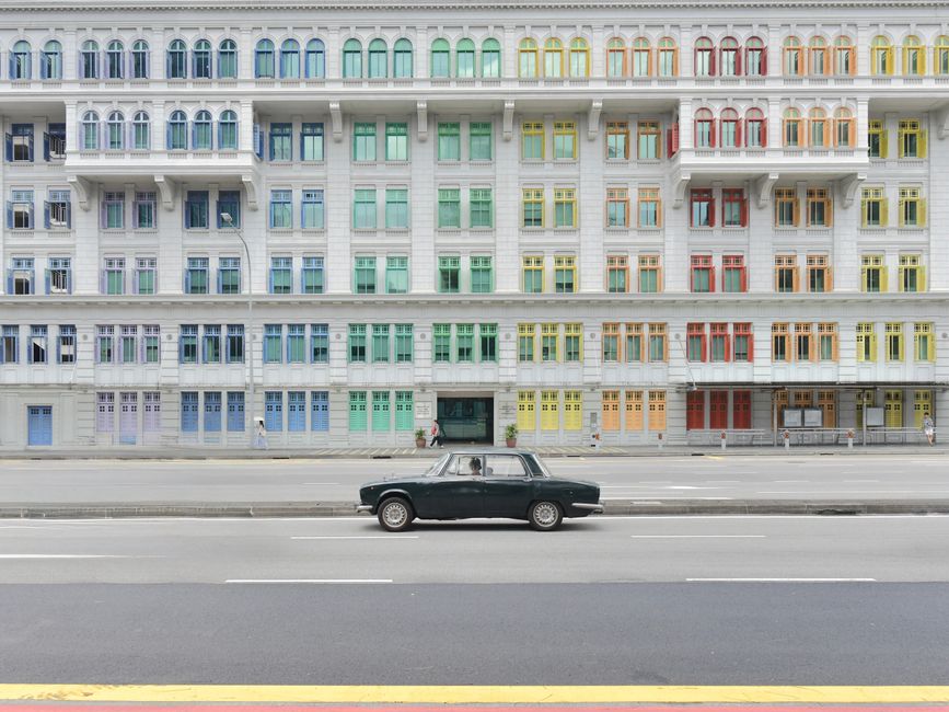 Vintage car parked in front of the vibrant Old Hill Street Police Station with colorful windows in Singapore.