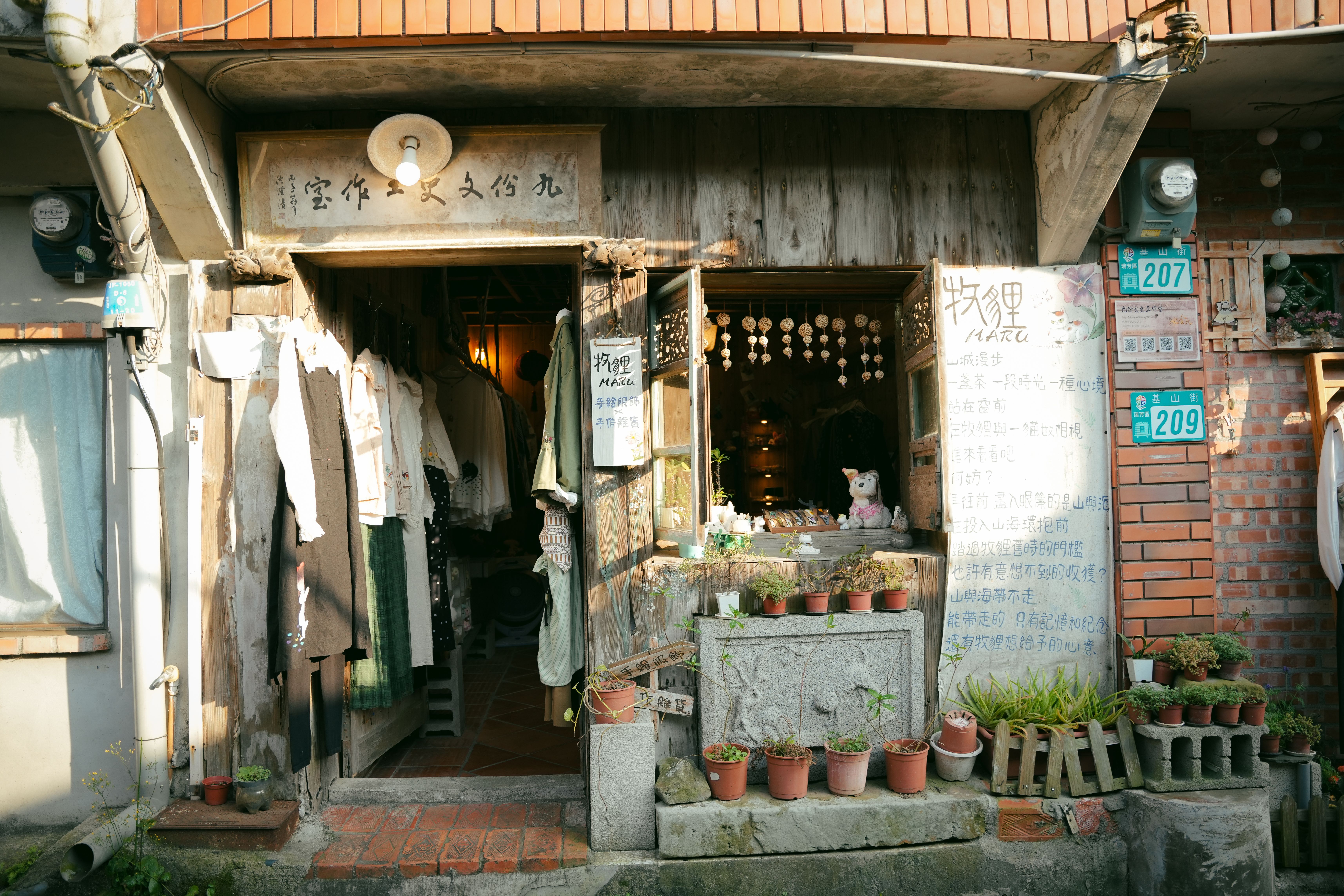 晴れた日に屋外に衣類や装飾品が展示されている魅力的なヴィンテージショップ。