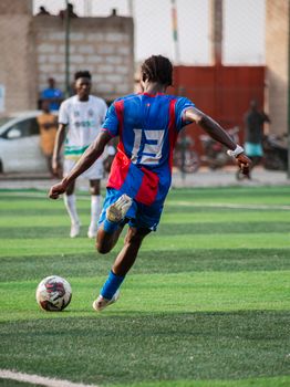 Dynamic action shot of a young soccer player kicking the ball on a turf field during practice.