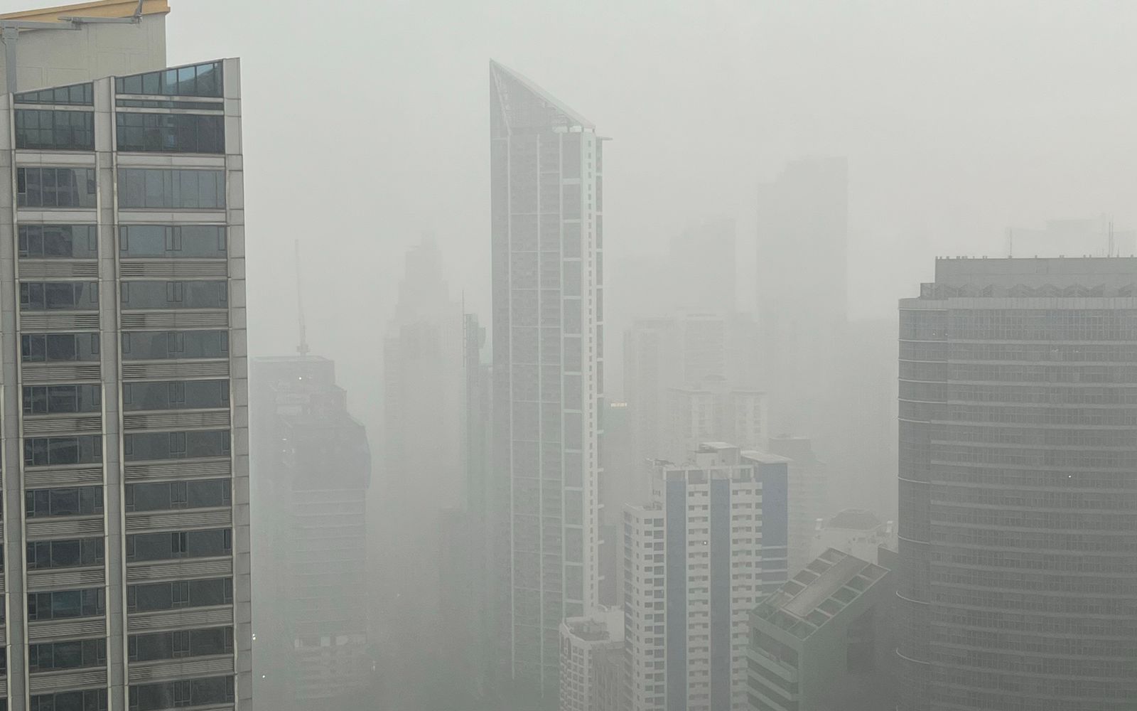 An aerial view of a city skyline where high-rise buildings fade into thick haze