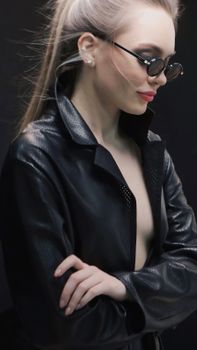 Portrait of a fashionable woman in sunglasses and leather coat.
