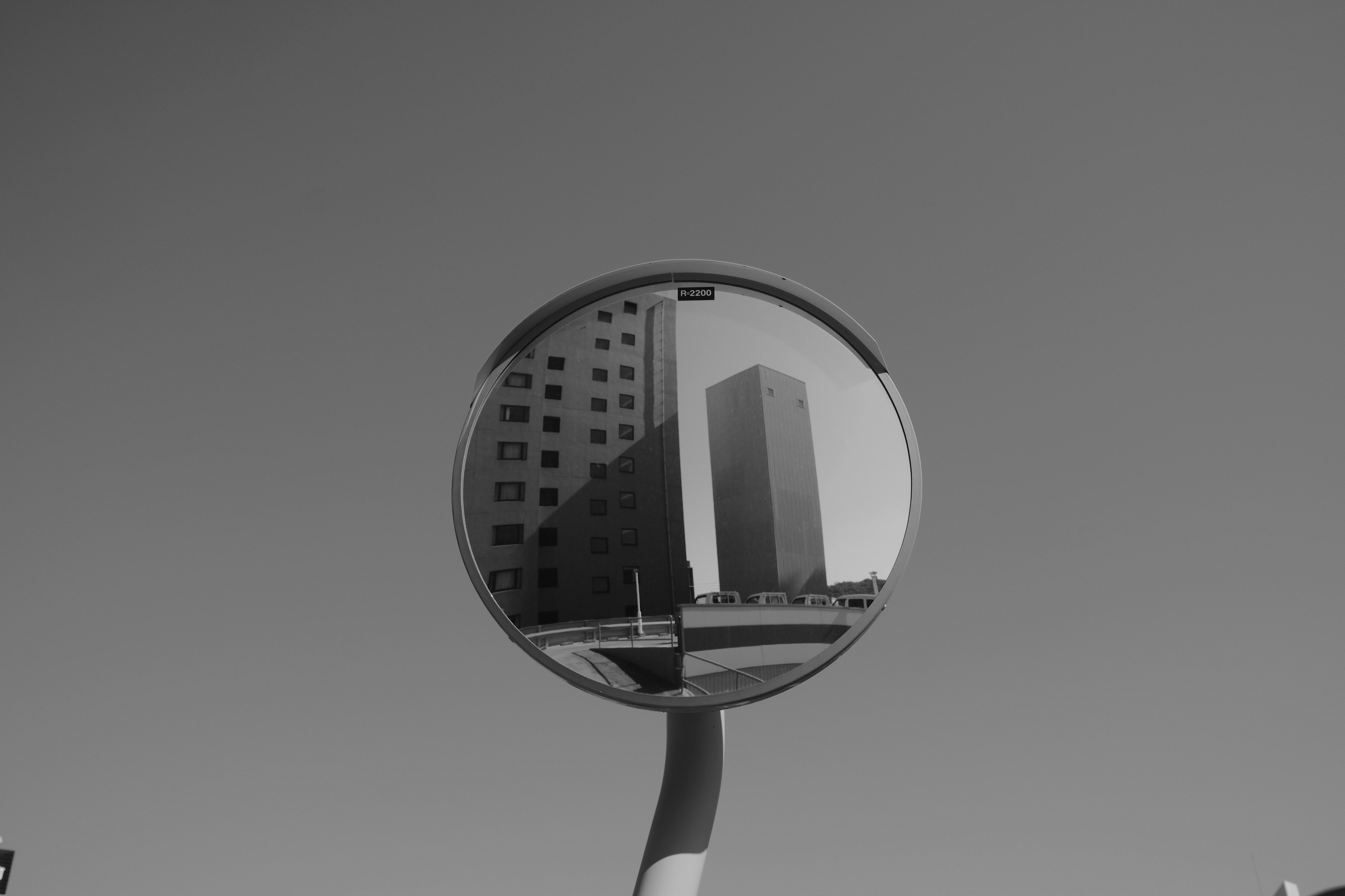 De franc Un paisatge urbà es reflecteix en un mirall de trànsit convex en blanc i negre. Foto d'estoc