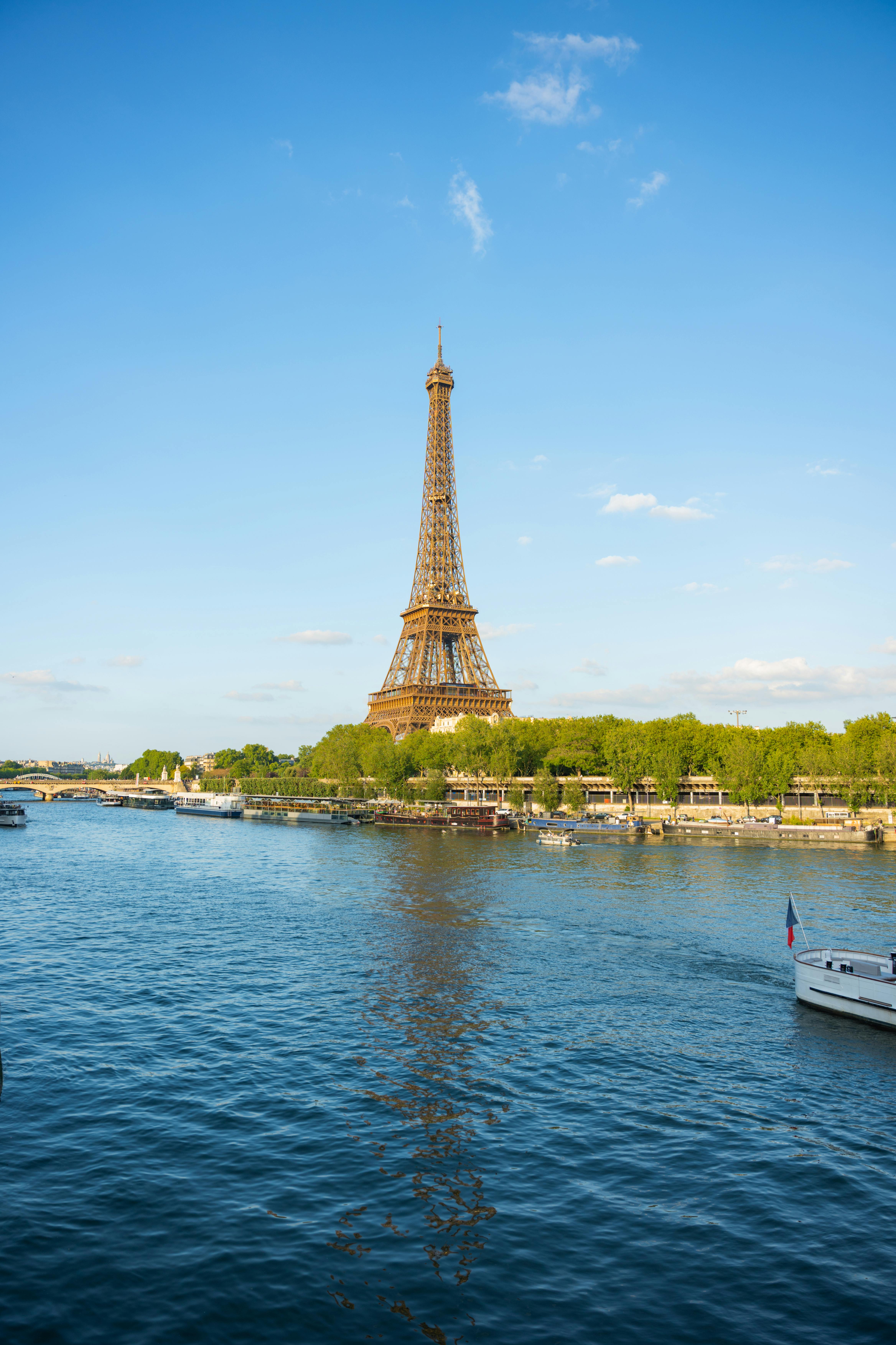 Scenic view of the Eiffel Tower with the Seine River under blue skies in Paris, France.