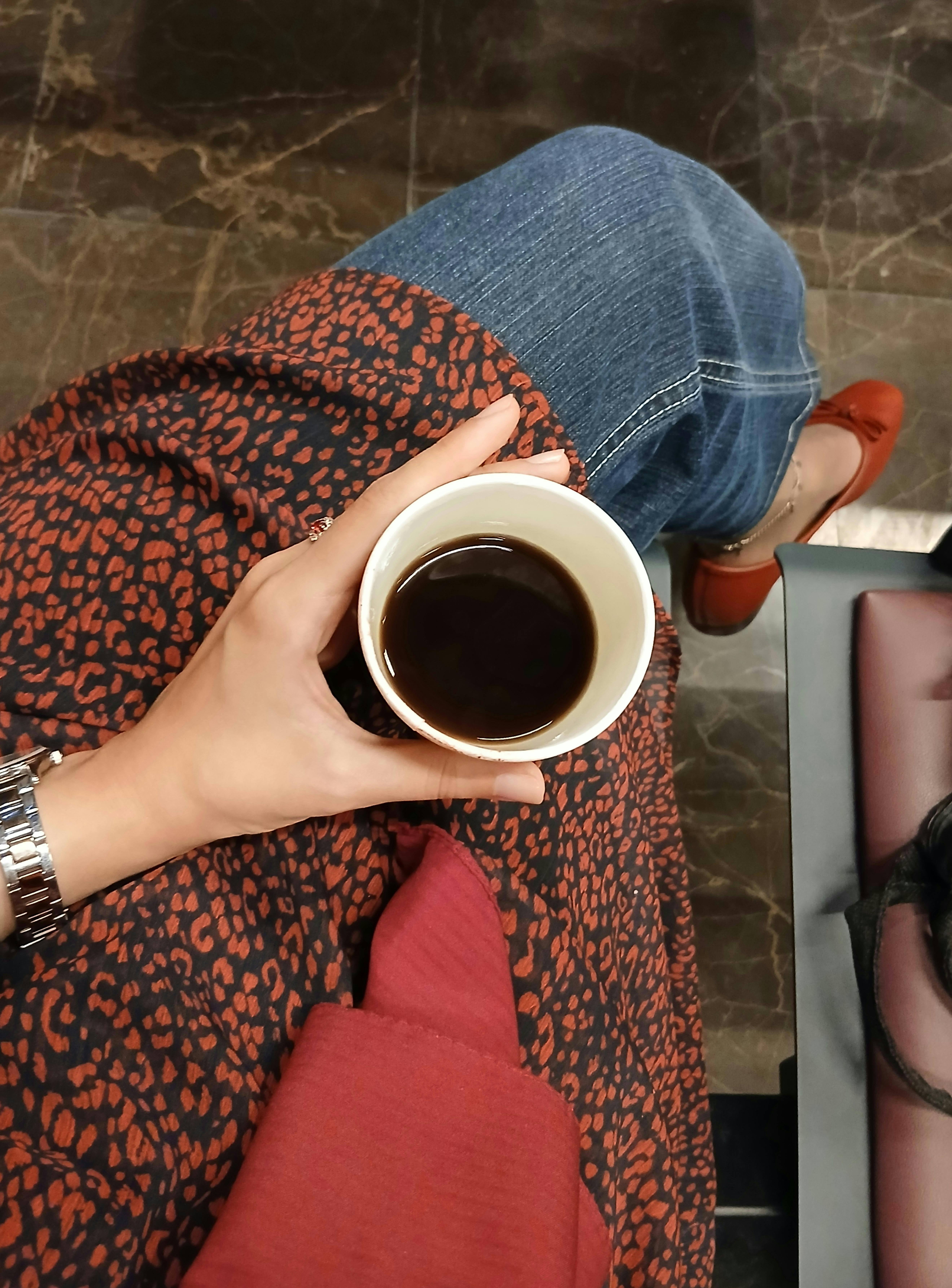 Top-down view of a person holding a cup of coffee, wearing cozy clothing, indoors.