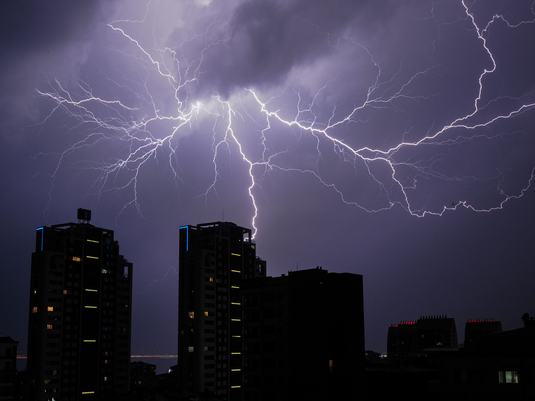 Stunning view of lightning bolts illuminating a cityscape at night, creating a dramatic and powerful scene.