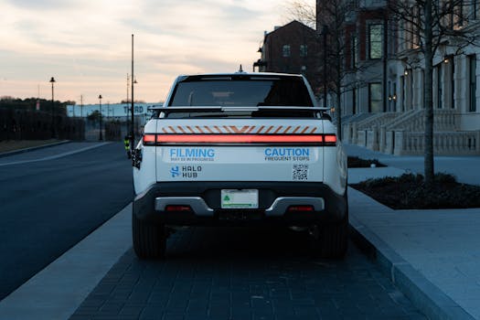 Rear view of a pickup truck on a city street at dusk, featuring caution signs.