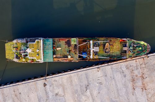 Free Aerial photograph of an old abandoned cargo ship docked at Jakarta port, highlighting its rusted and weathered structure. Stock Photo