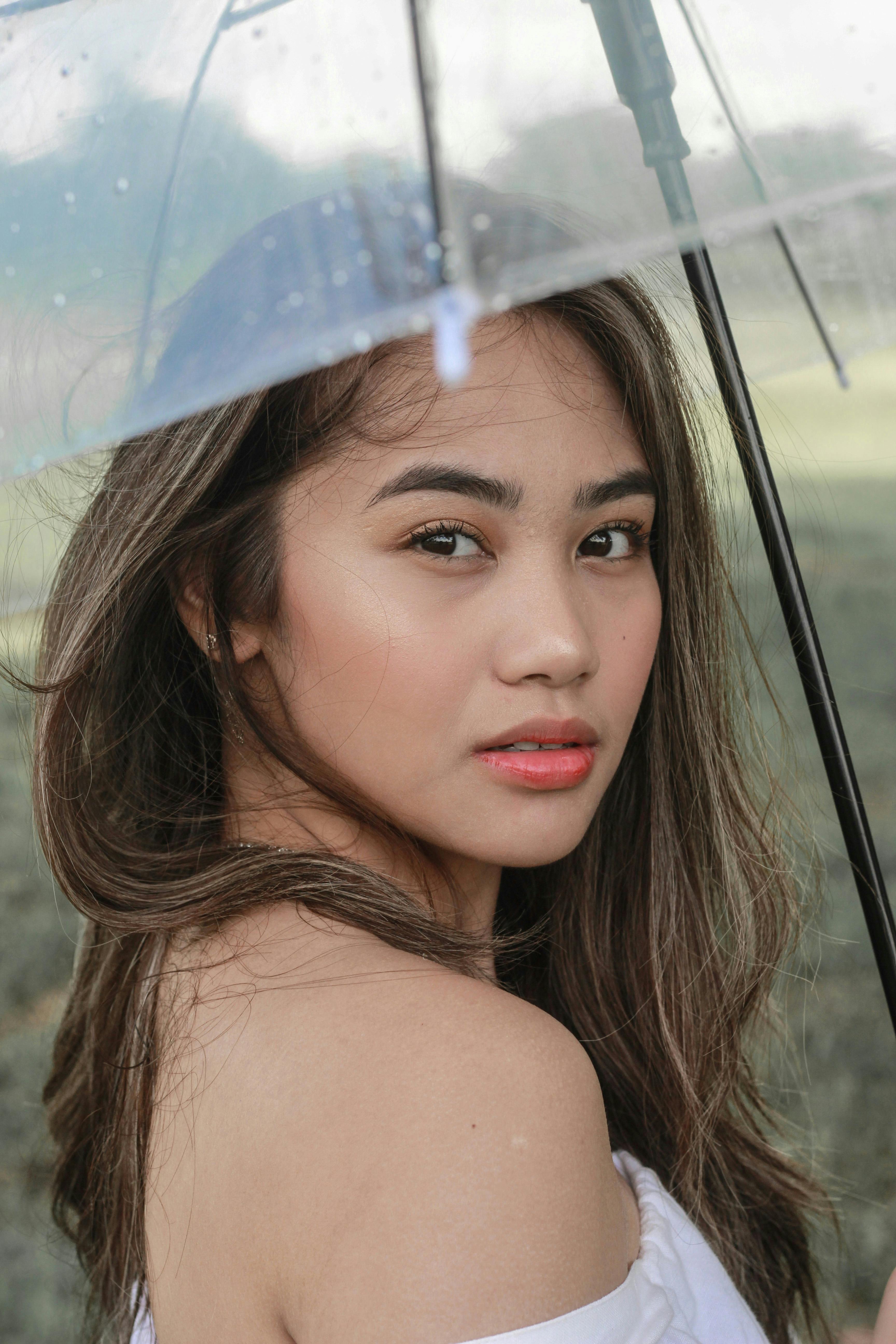 优雅的女人撑着透明伞，在户外展示着时尚与美丽