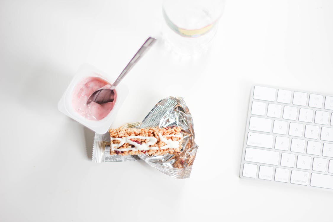 Flat Lay Photography of Yogurt With Pack of Crackers and Apple Magic Keyboard