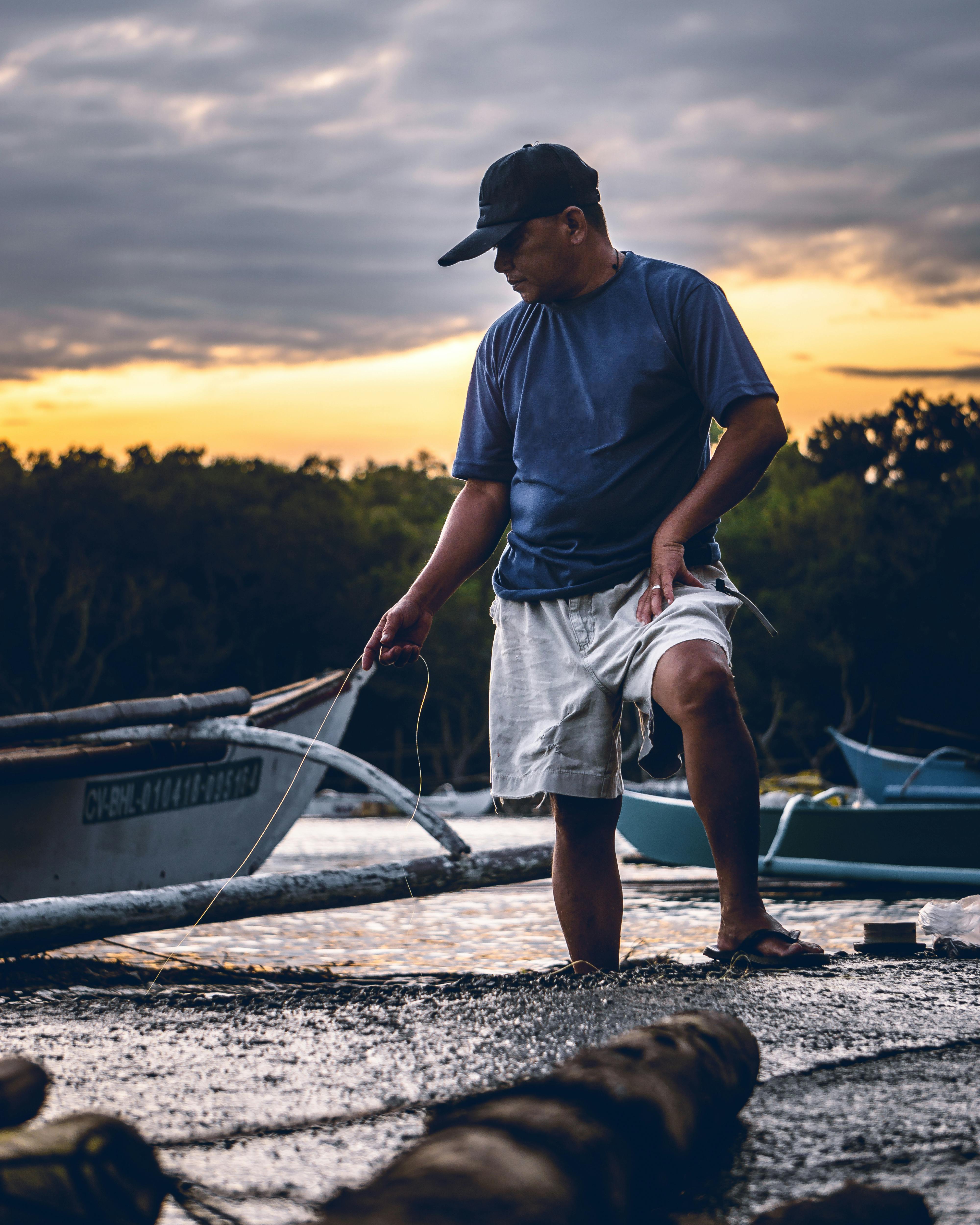 一名渔民在日落时分的绚烂霞光中，驾船在岸边劳作