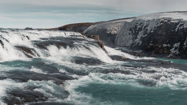 Discover the dramatic beauty of an Icelandic waterfall cascading powerfully over icy rocks.