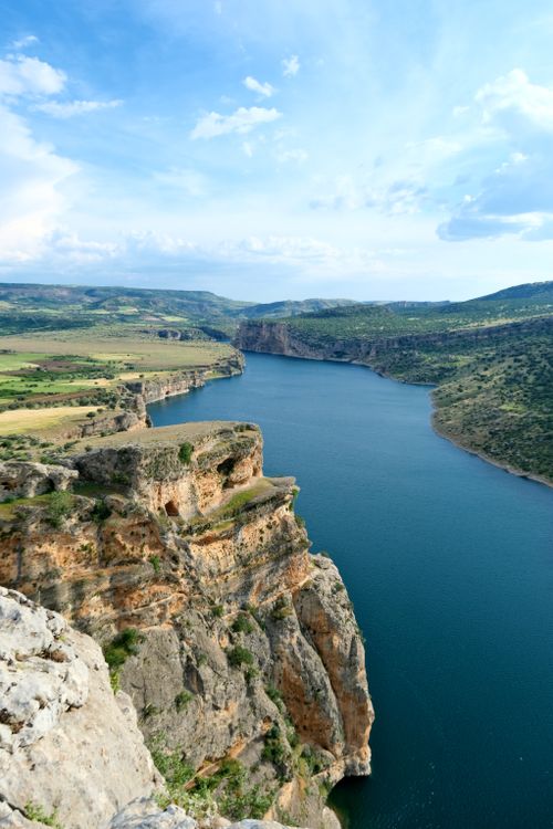 Free Breathtaking aerial view of a tranquil river canyon surrounded by lush cliffs and clear blue skies. Stock Photo