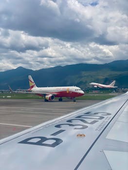 Airplanes on the runway and taking off, with scenic mountain backdrop and cloudy sky.