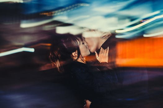 Artistic photo of a couple kissing at night with a dynamic blurred effect, capturing motion and emotion.