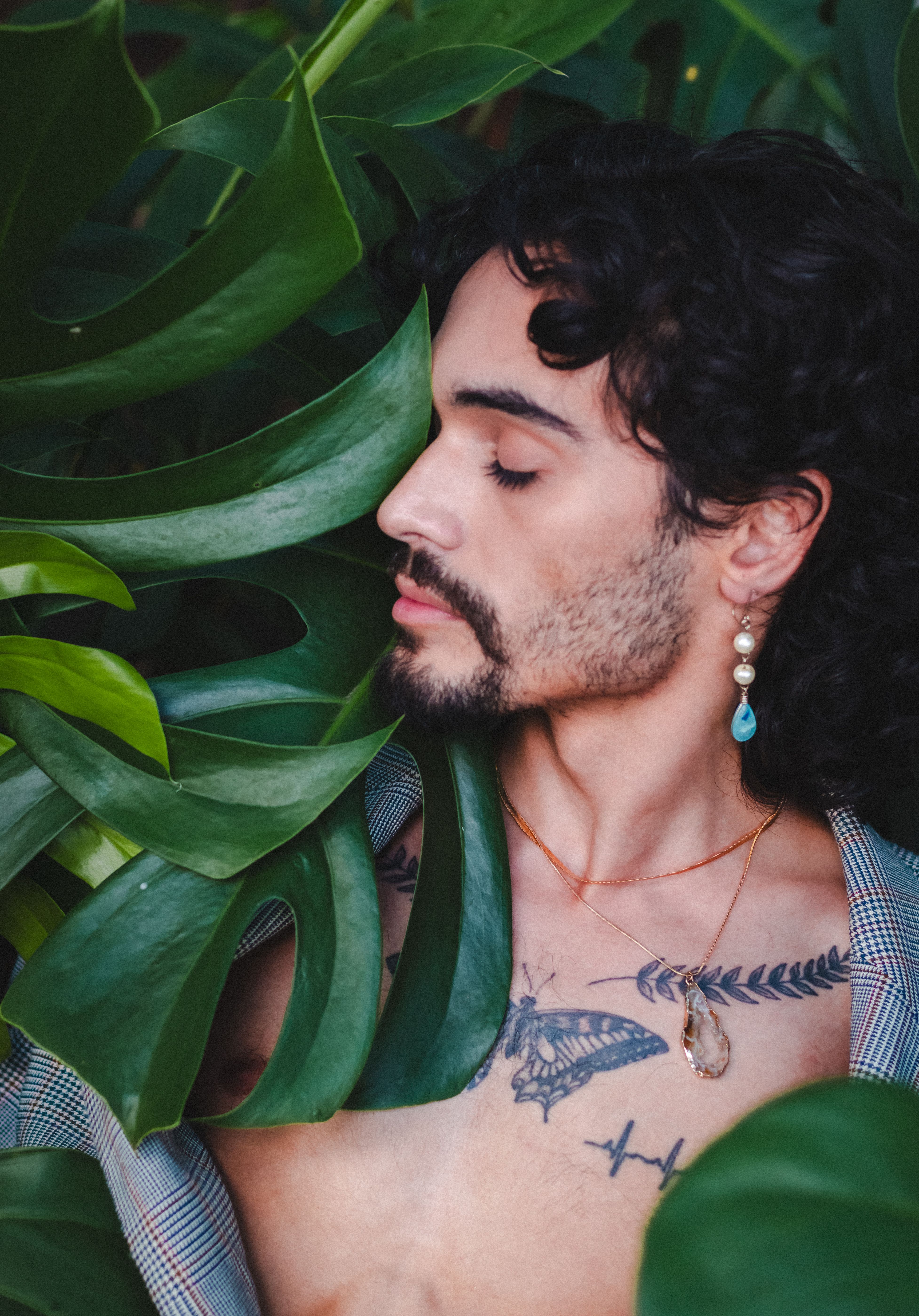 A serene portrait of a man surrounded by tropical leaves, emanating natural beauty.