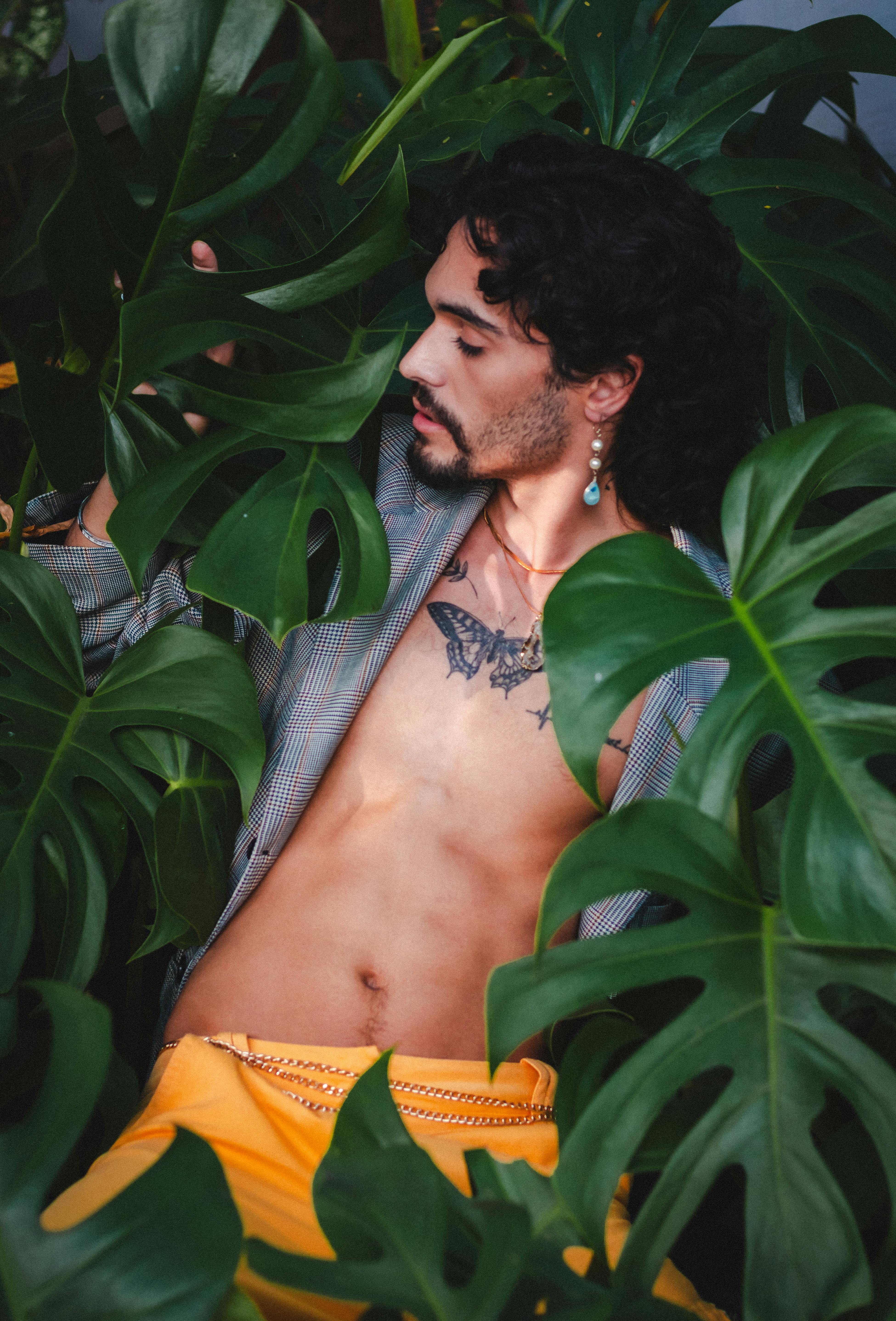 A captivating portrait of a man surrounded by green foliage, showcasing natural elegance and style.