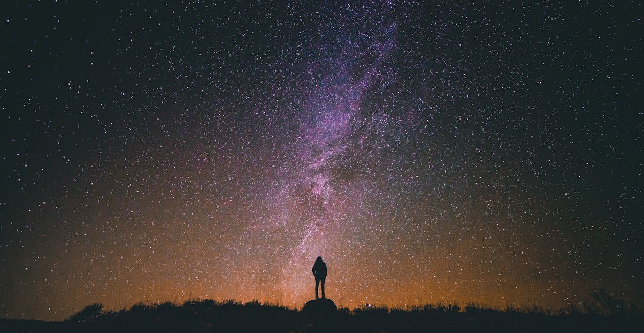 Silhouette Photo of a Person Standing on Rock